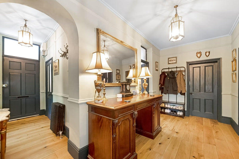 Foyer with wooden desk, mirror, and coat rack.
