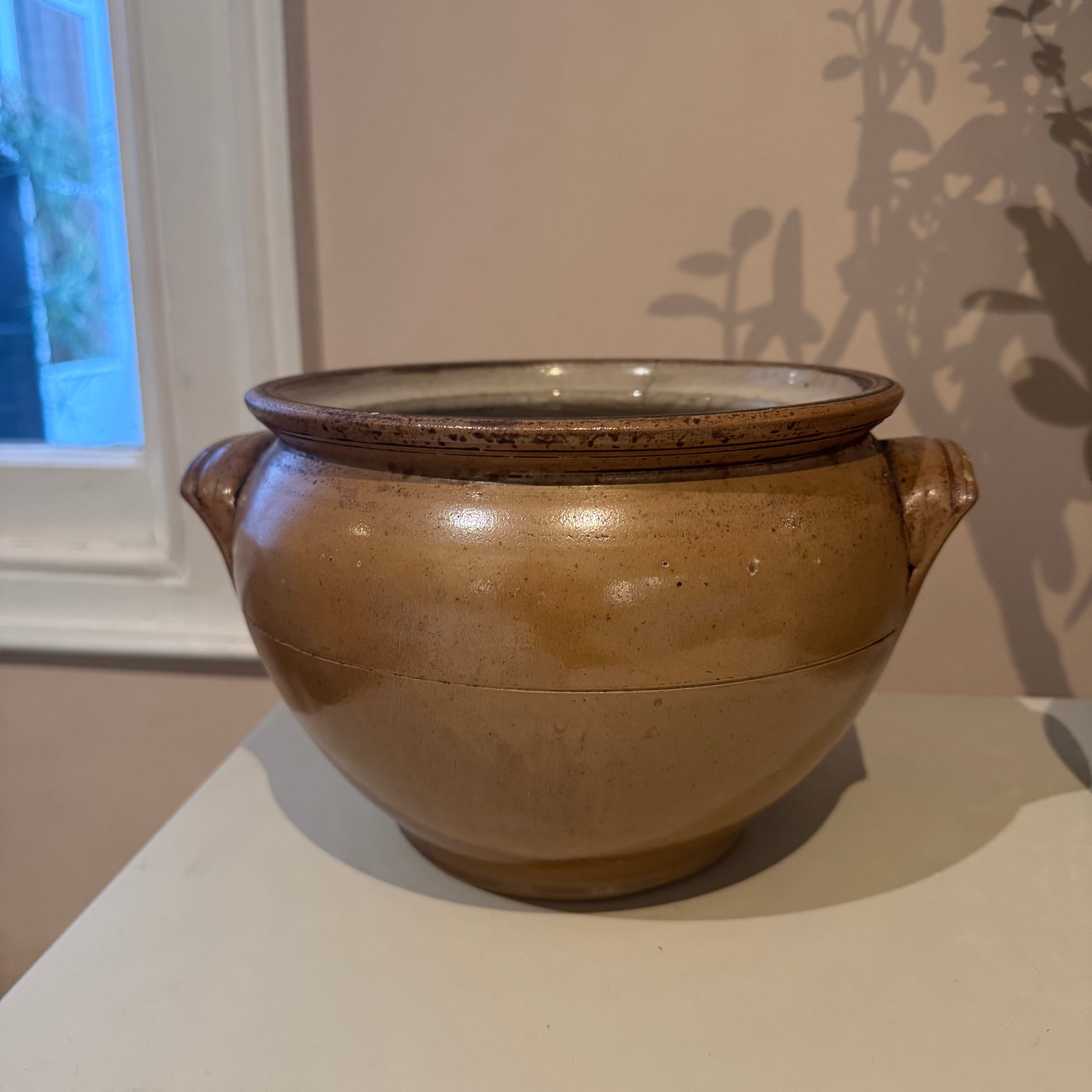 Brown ceramic pot with handles on a white surface