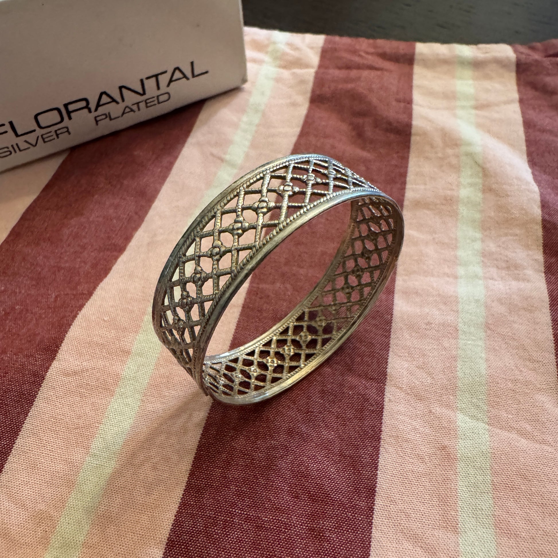 Silver napkin ring on a striped fabric with 'Florantal' packaging in the background