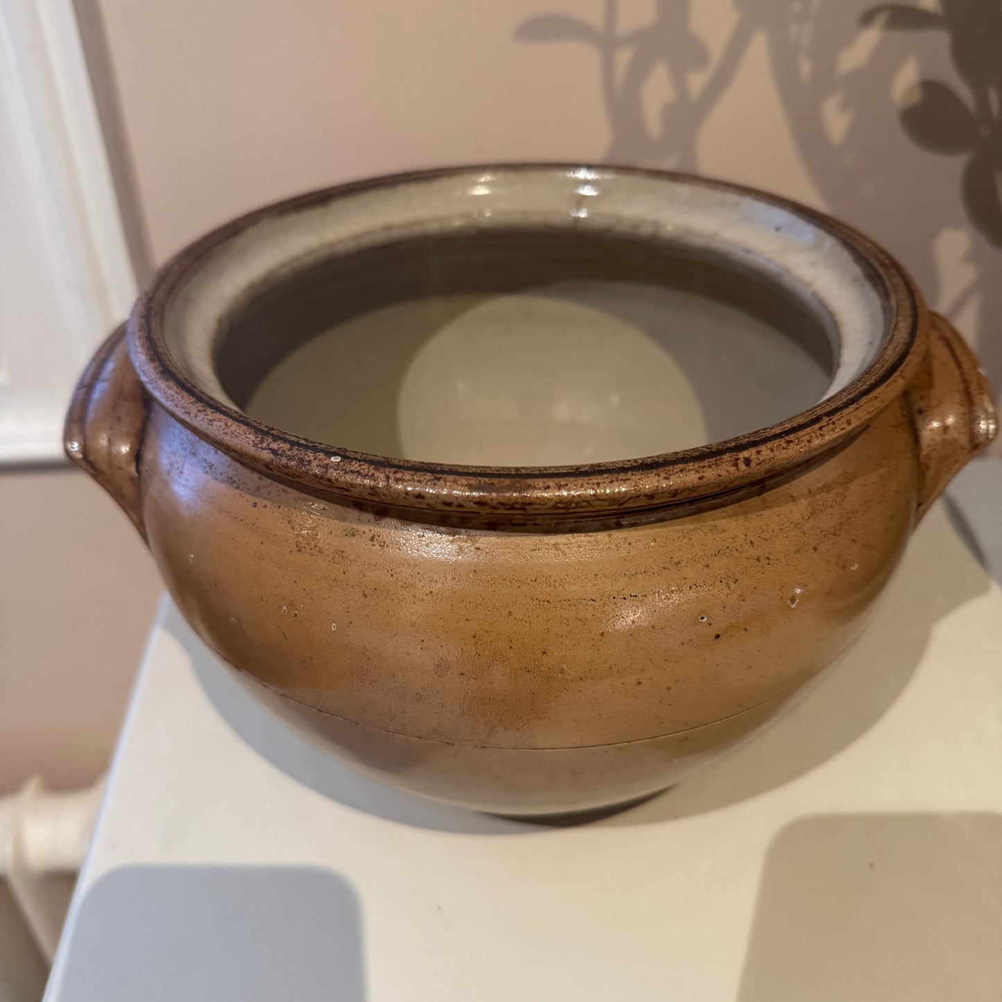 Brown ceramic pot on a white surface with a neutral background