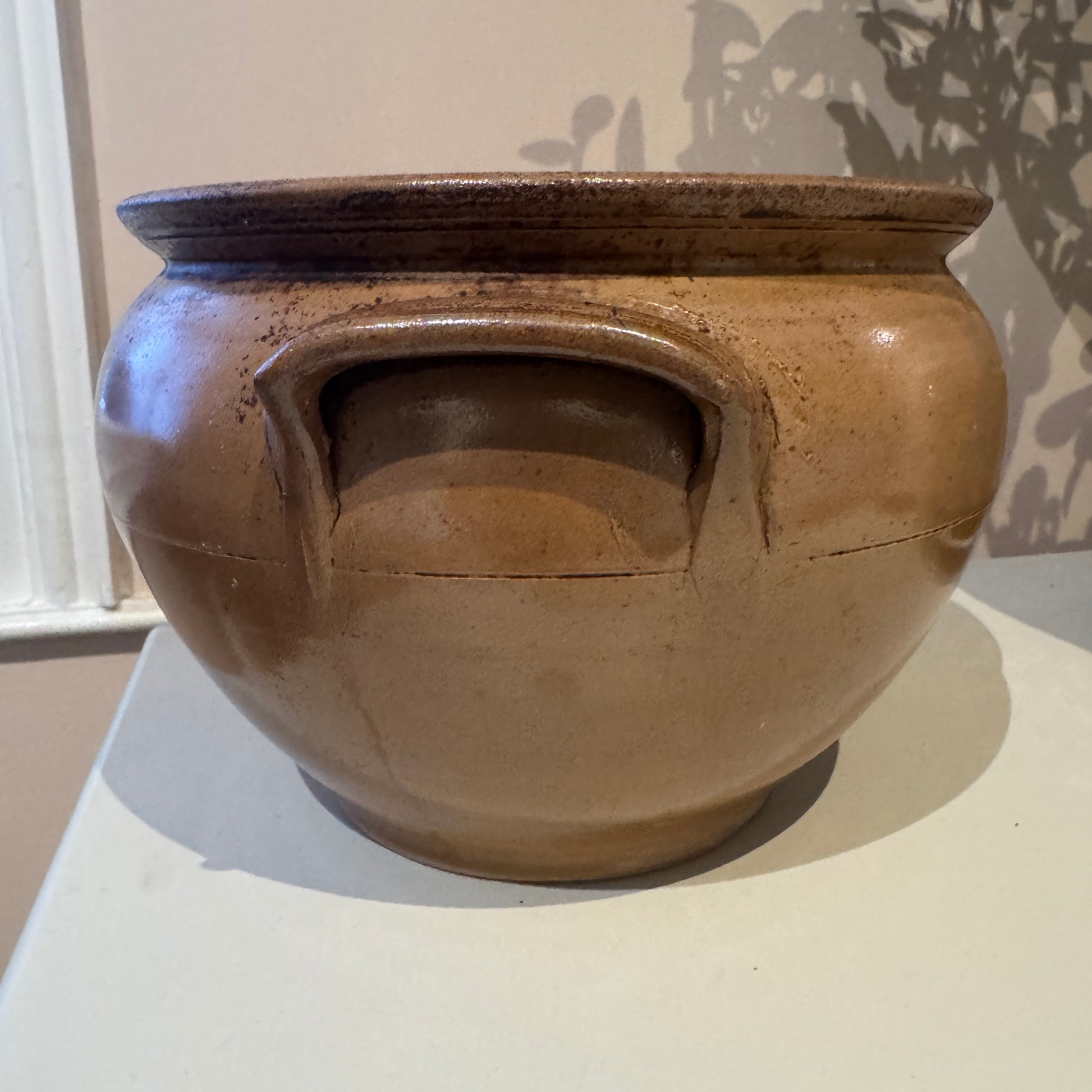 Brown ceramic jar with handles on a white surface