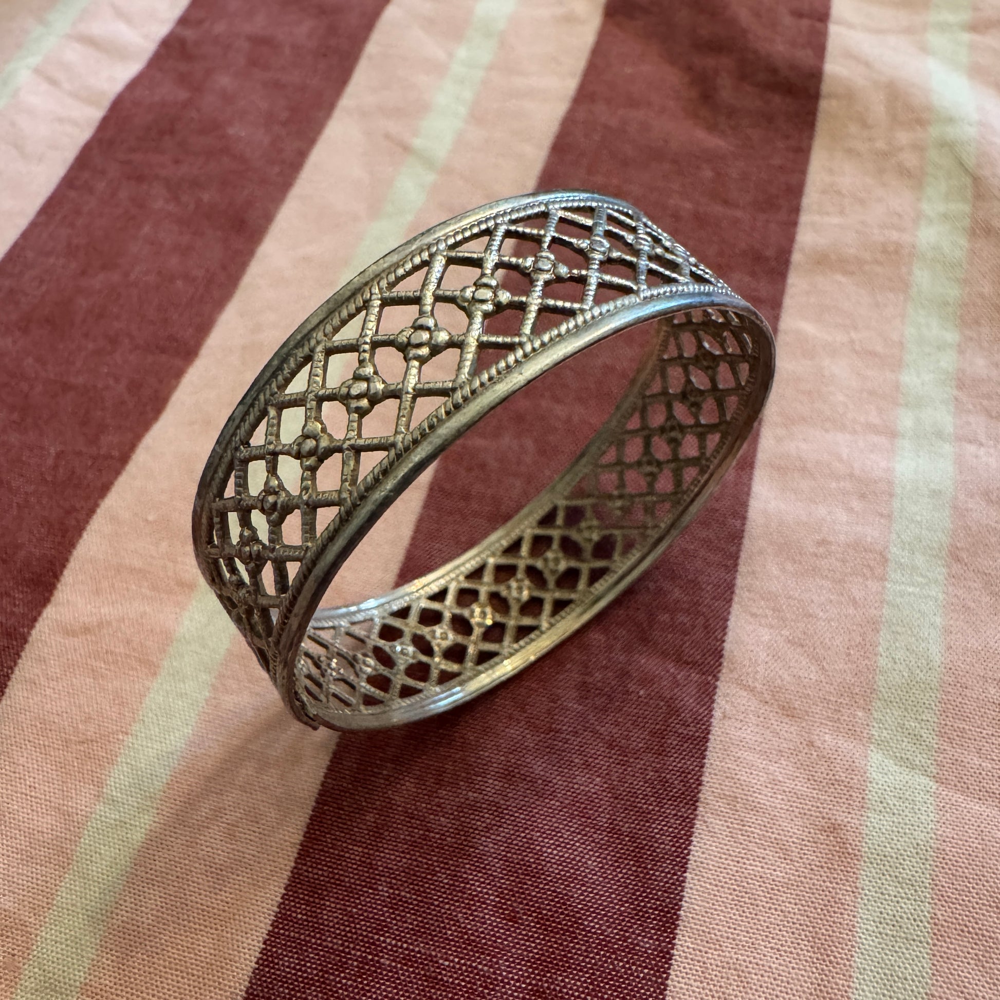 Decorative metal napkin ring on a striped fabric background