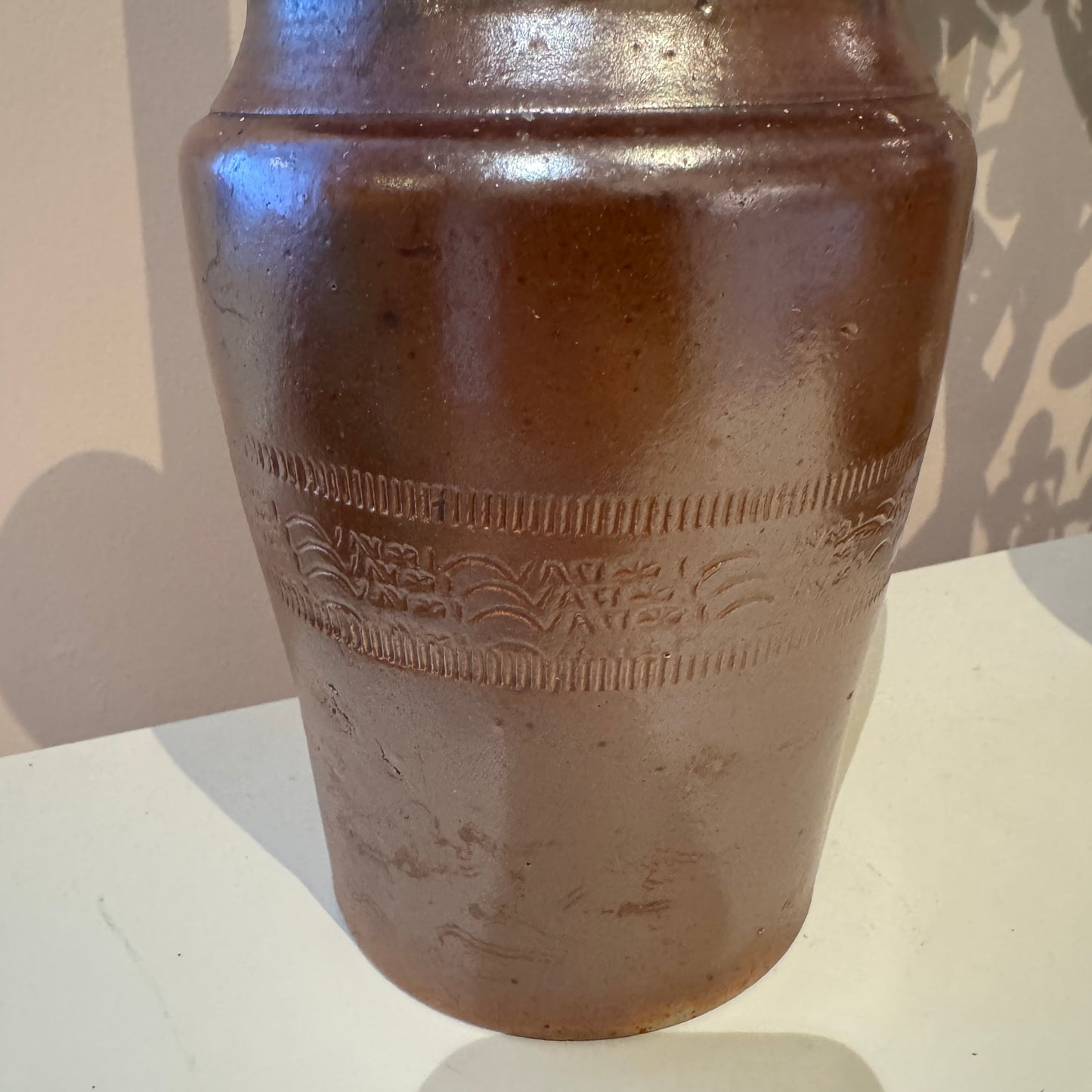 Brown ceramic vase with embossed design on a white surface