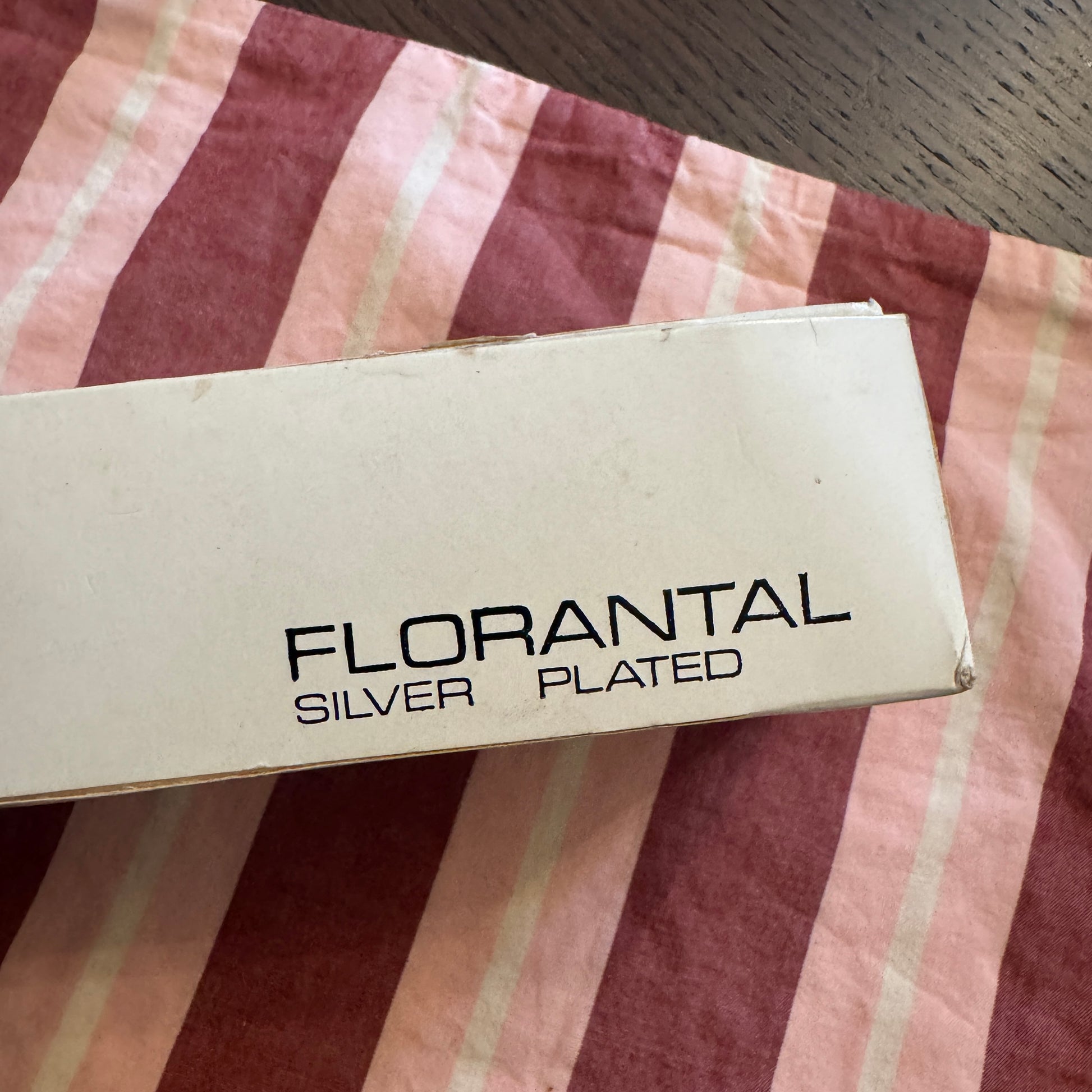 Florantal silver plated product packaging on a striped fabric background