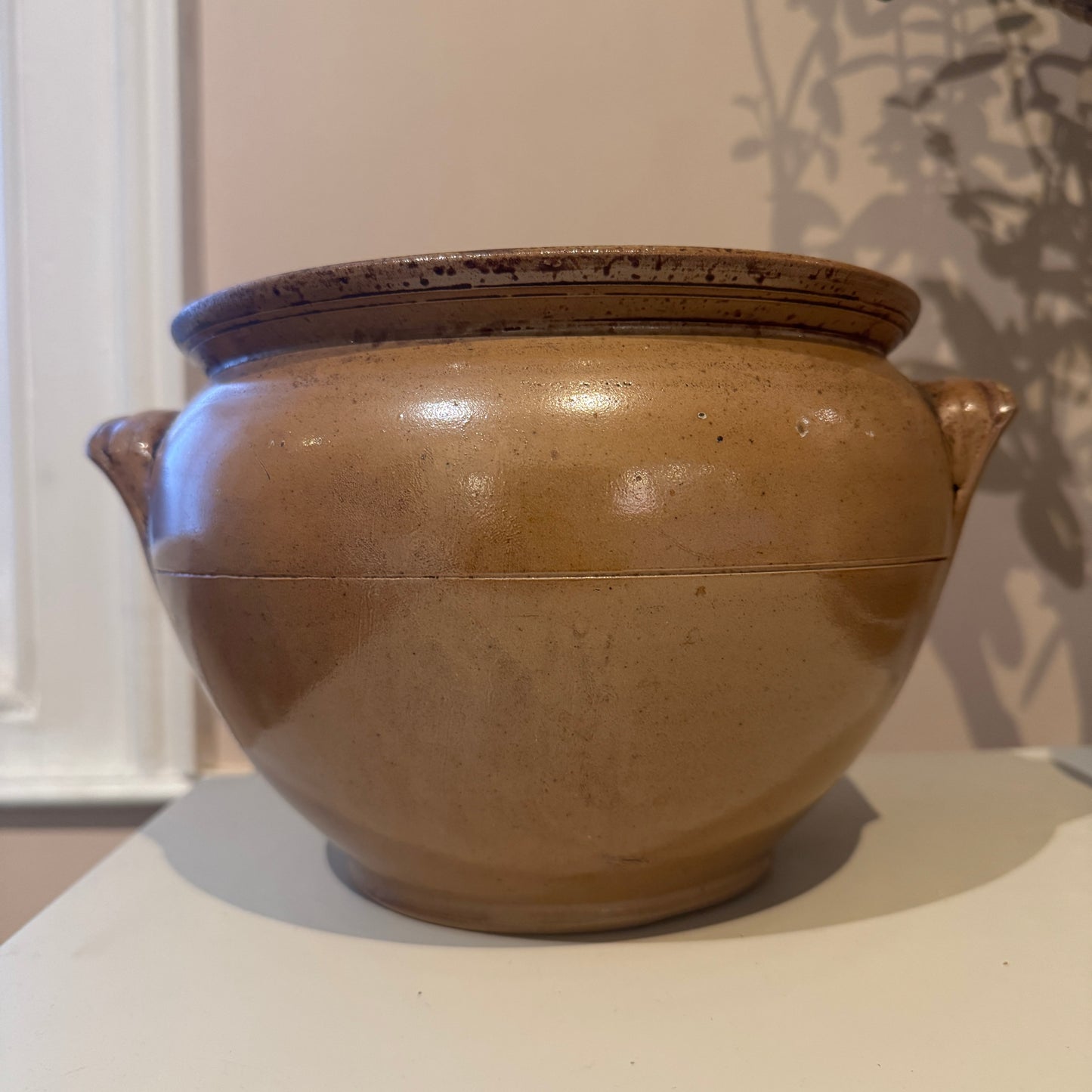Brown ceramic jar with lid on a white surface