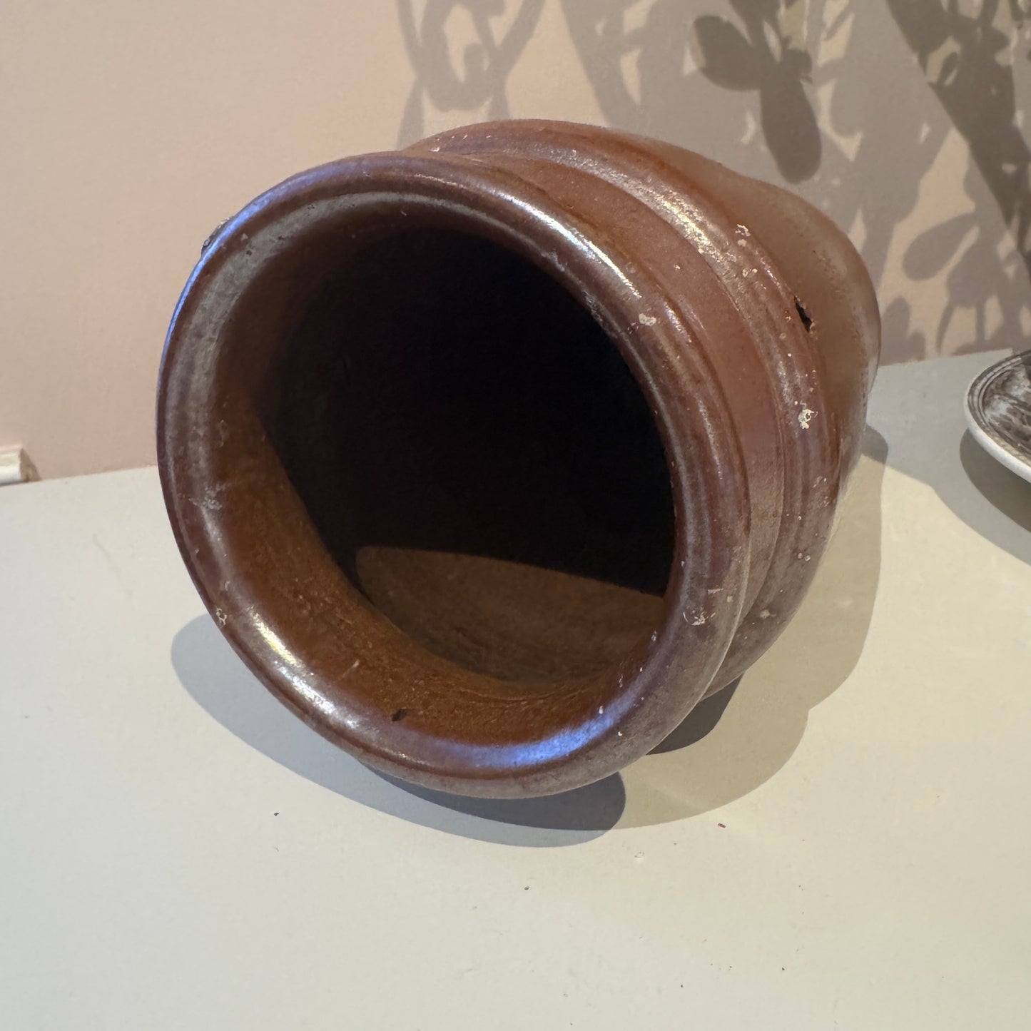 Brown ceramic pot on a white surface with a neutral background