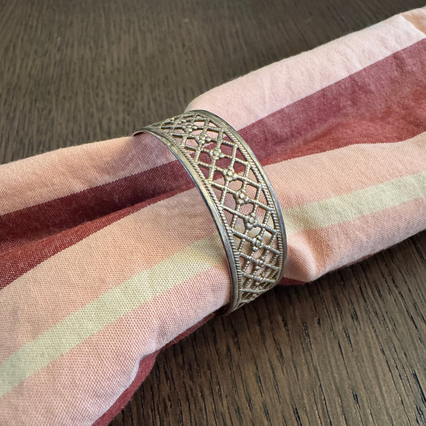 Decorative napkin ring on a striped napkin with a wooden surface background
